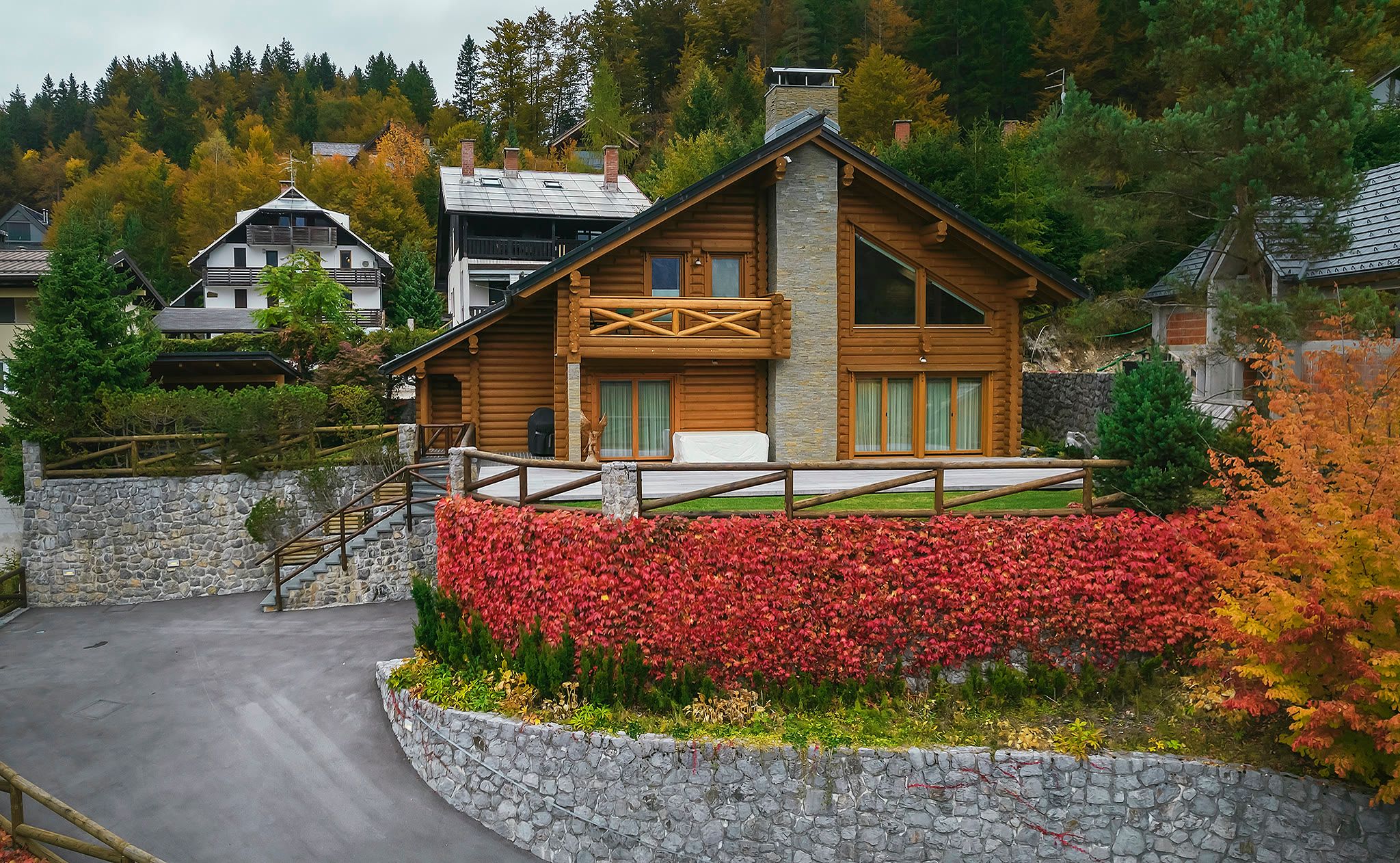 Aerial view of the chalet's front elevation, showing the gabled roof, tall glazing, a balcony, and the creeper-covered wall below.