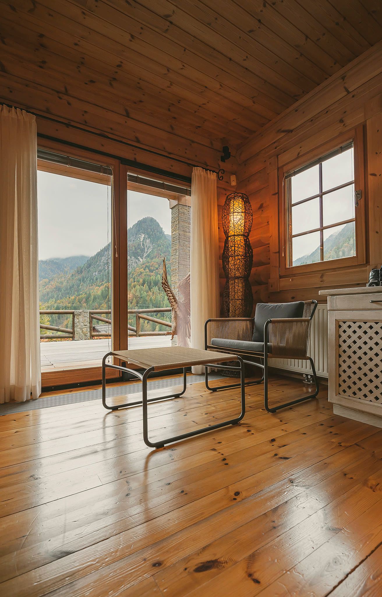 A room opening onto a balcony through sliding doors, with a mountain ridge visible beyond.