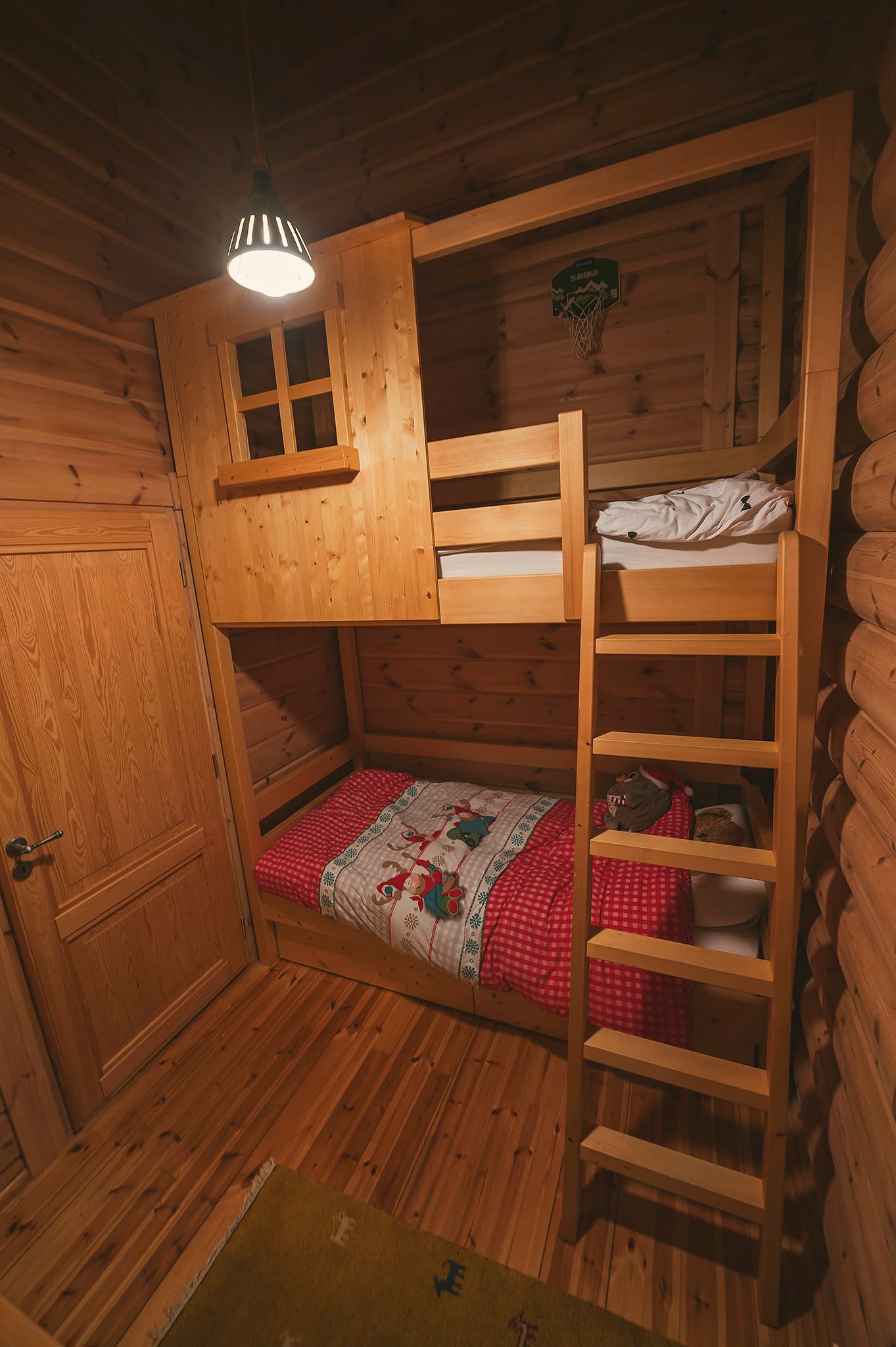 The children's room with a timber "hiška" house-frame bunk bed, a ladder, and red bedding.