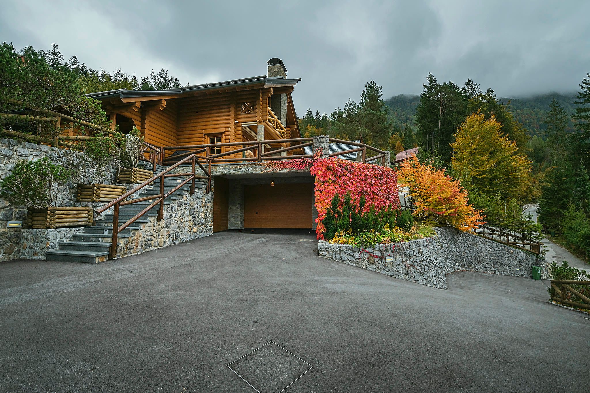 Exterior view across the driveway showing the full gable end of the chalet, the crimson creeper wall, and autumn trees.