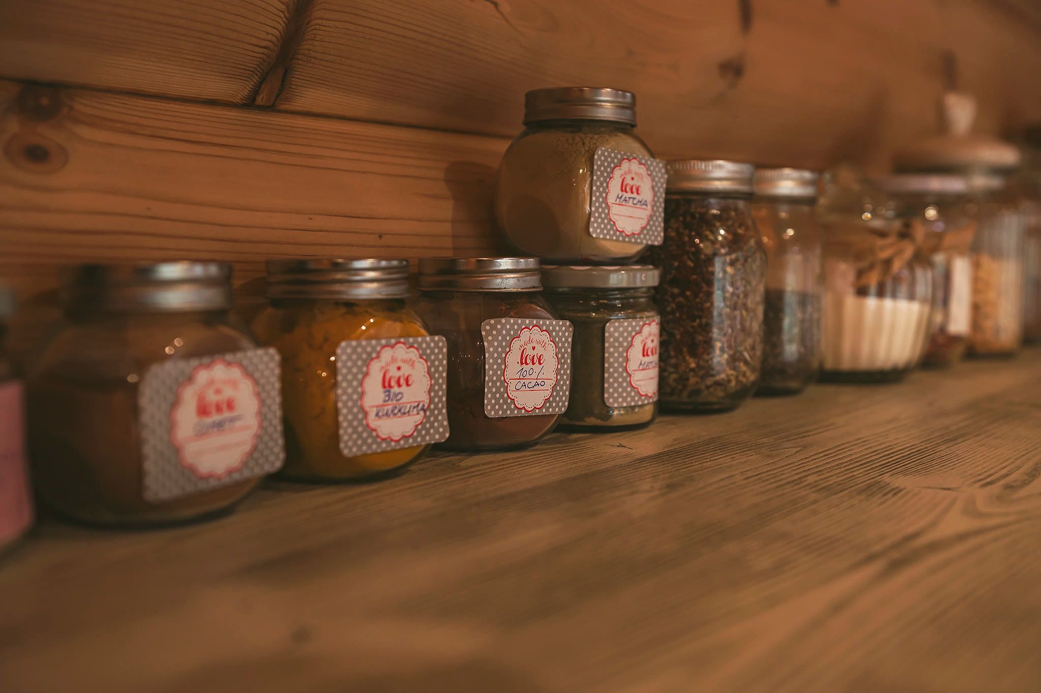 A row of labelled preserve jars on a timber shelf.