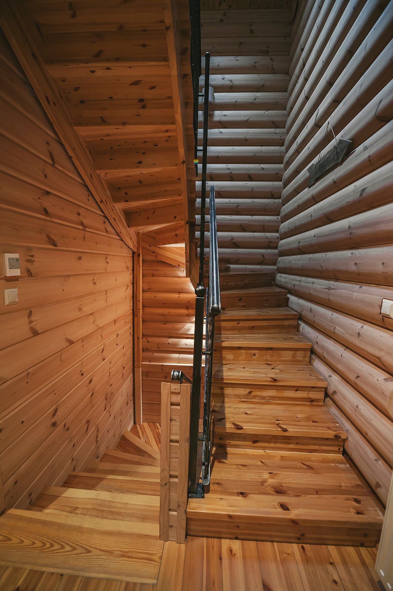 A timber staircase detail set against a round-log wall.