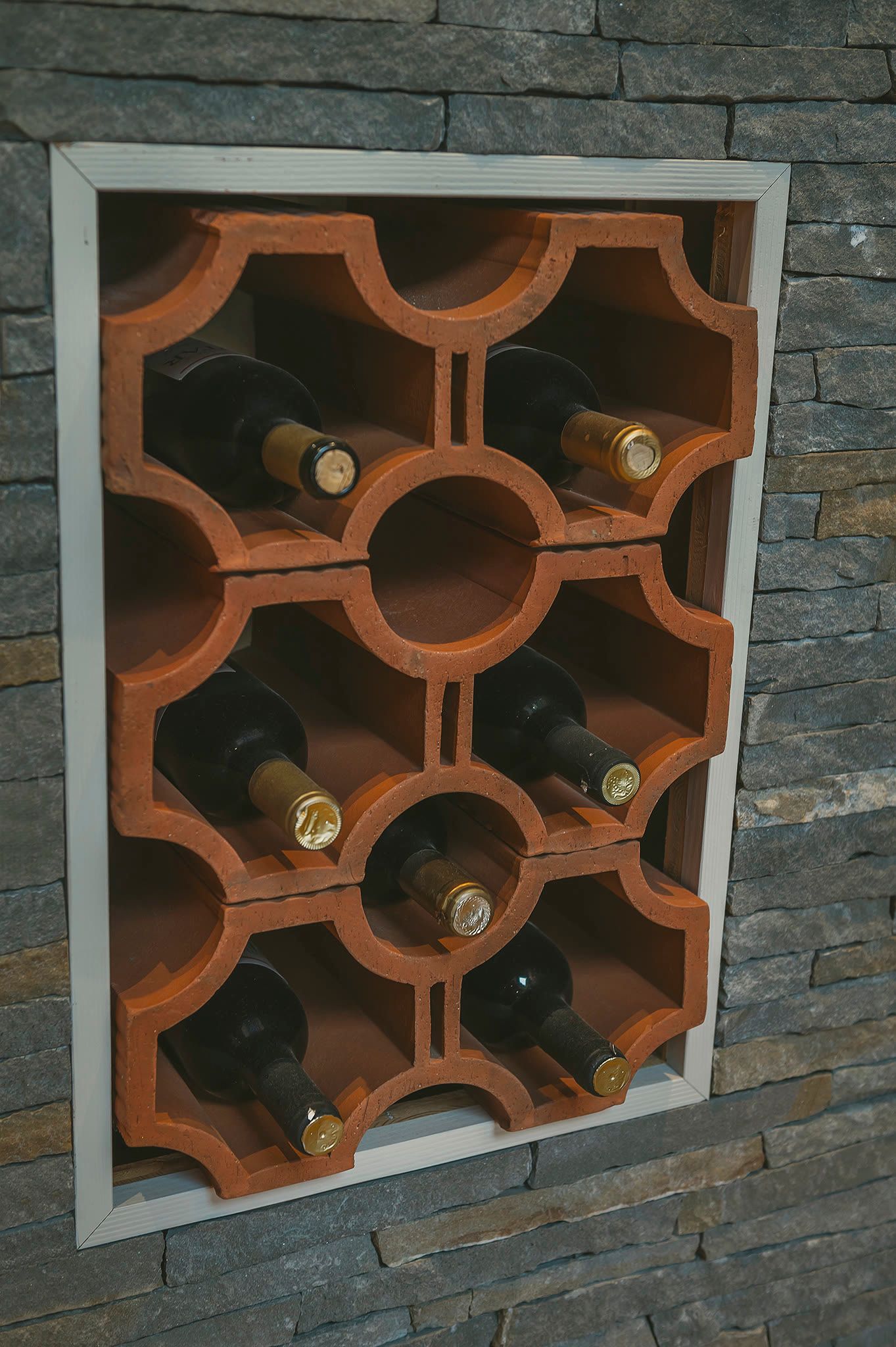 A wine rack recessed into the stone wall, holding stored bottles.
