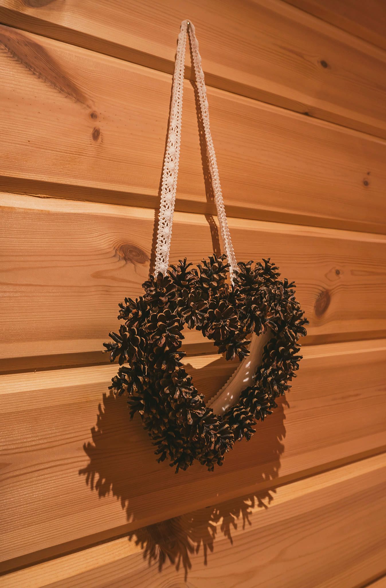 A dried-flower heart wreath hanging on a log wall.